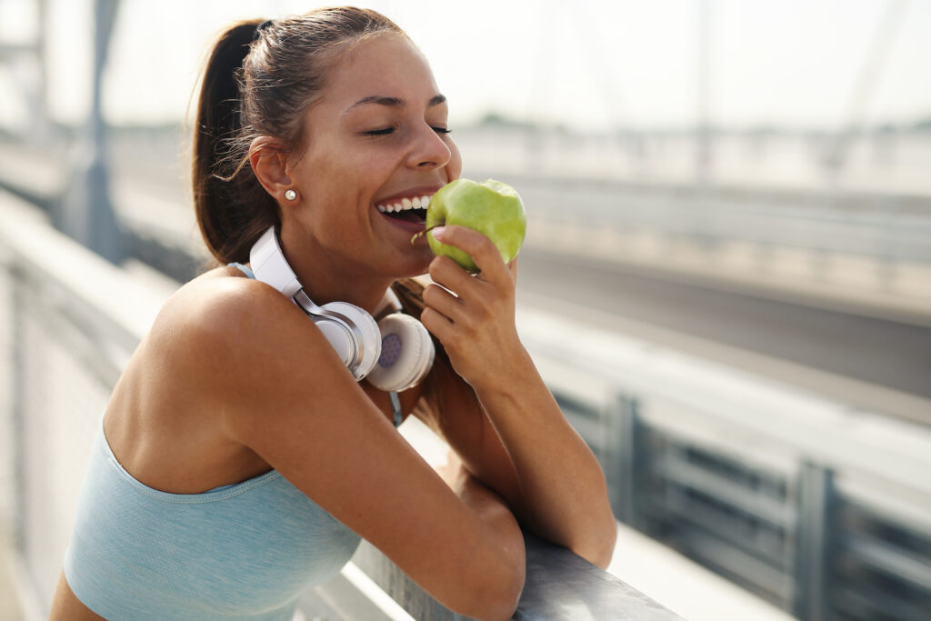 Young woman in sporty clothes practicing mindful eating with an apple