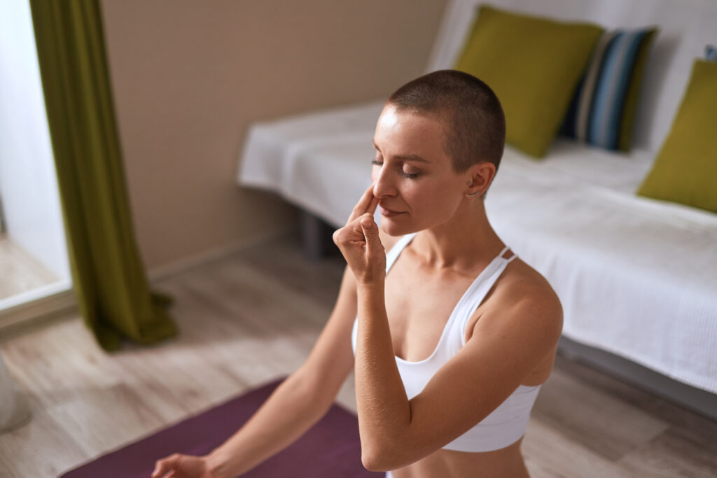 Yoga instructor sitting on a yoga mat and doing alternate nostril breathing